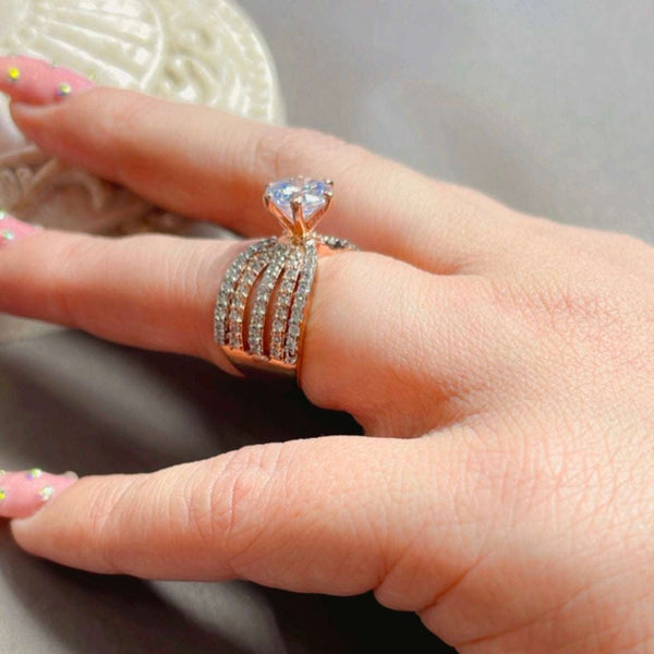 Elegant rose gold statement ring featuring a large heart-shaped clear gemstone and multiple rows of sparkling stones, worn on a woman’s finger with detailed nail art.