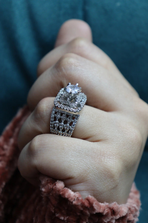 Close-up of a hand wearing a sparkling silver-toned statement ring featuring a floral-inspired design and multiple crystal embellishments.